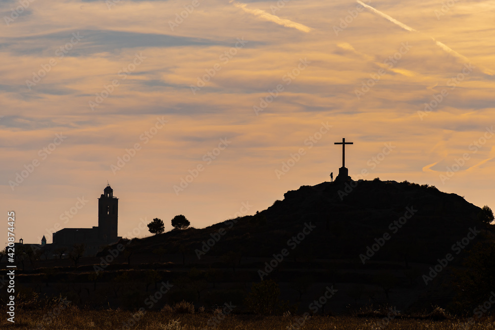 silhouette of a woman on the top of a mountain at the foot of a cross