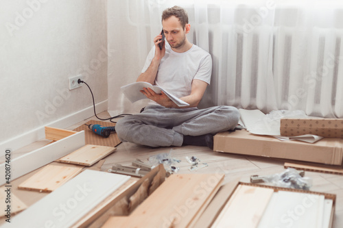 Fotografie Man customer calls to help center at home during assembling new furniture, calling for a master