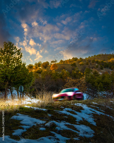 Car driving through hills on a snowy and sunny day with motion blur, evening. Lake Eymir, Ankara, Turkey.