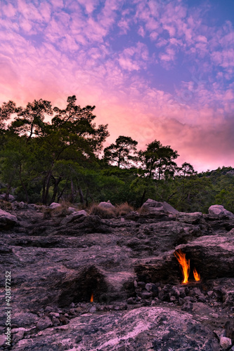 A sunset view from the Yanartaş hilltop in south Turkey with naturally burning fire in the foreground and colorful clouds above