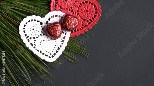Chocolate Hearts on Paper Hearts and Pine Branches Isolated on a Black Background | Valentine's Day Chocolate | Valentine's Day Chocolate Hearts | Valentine's Candy | Chocolate Isolated