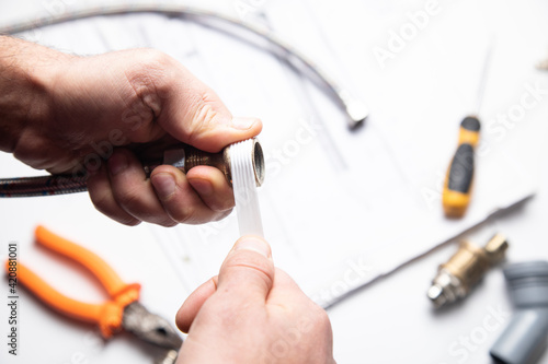 Photography Plumber putting seal tape on a thread of a plumbing fitting