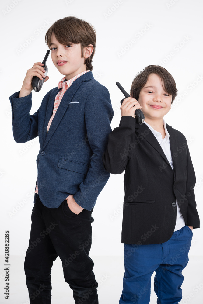 Two young happy managers in suits speaking over portable radio, white background Two young happy managers in suits speaking over portable radio, white background
