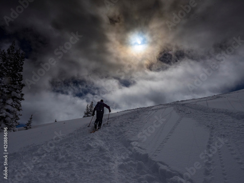 Silhouetted skier climbing for powder, bluebird day in Mountains near Park City, Utah, USA. © Danita Delimont