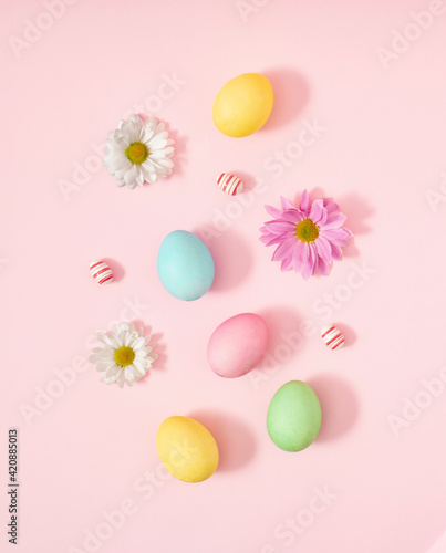 Creative decoration of Easter pastel colored eggs with spring fresh flowers on pink background. concept flat lay.