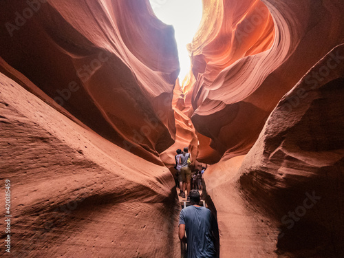 People in water shaped smooth sandstone walls to unusual curves and adges in antelope national park in arizona, america