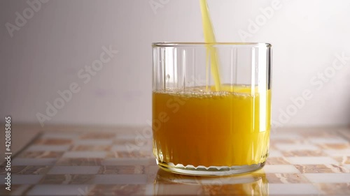 A beautiful glass glass into which orange juice is poured. Light background