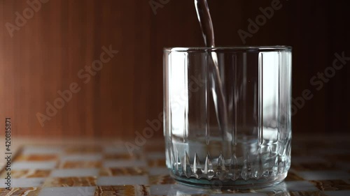 A beautiful glass jug into which clear water is poured. Dark background