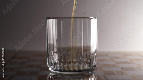A beautiful glass glass into which orange juice is poured. Light background