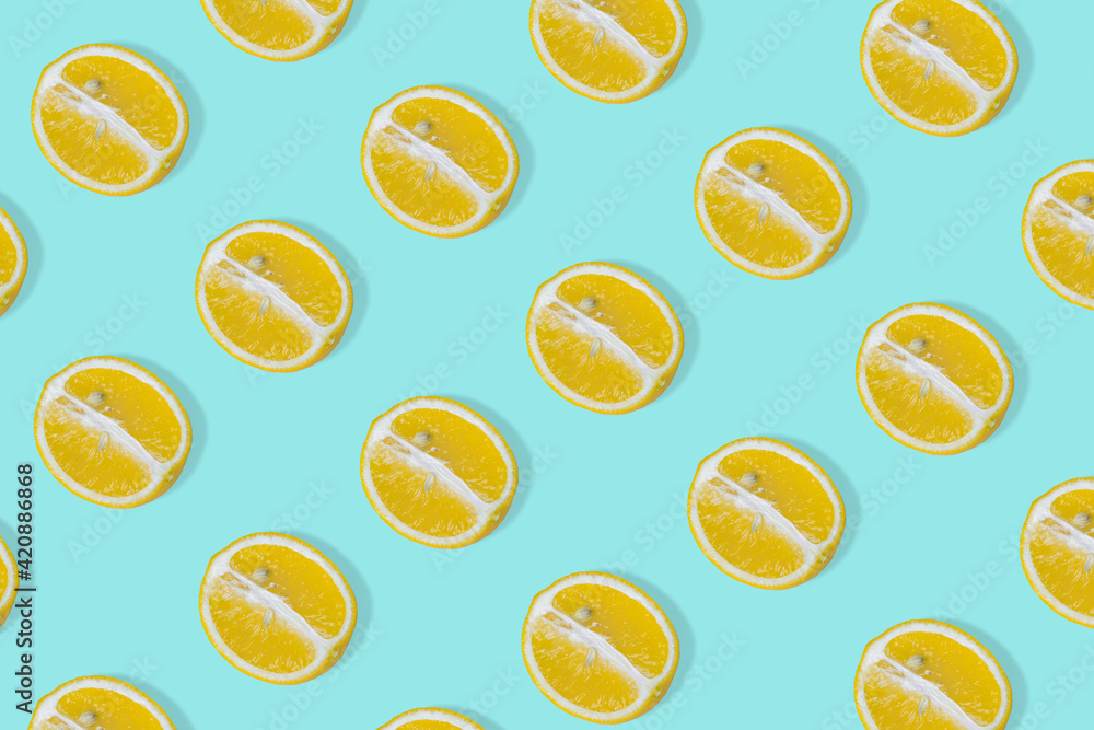 Creative summer pattern with yellow lemon slice on bright light blue background Creative summer pattern with yellow lemon slice on bright light blue background