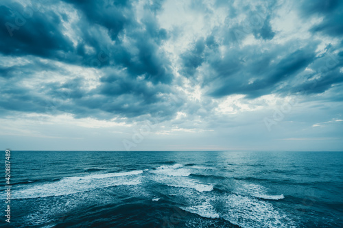 Fototapeta Naklejka Na Ścianę i Meble -  Dark blue clouds and sea or ocean water surface with foam waves before storm, dramatic seascape.