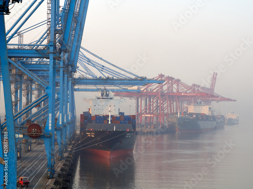 India, Mumbai Port Trust - 25 January, 2017: View to moored container vessels with port cranes during the morning fog.