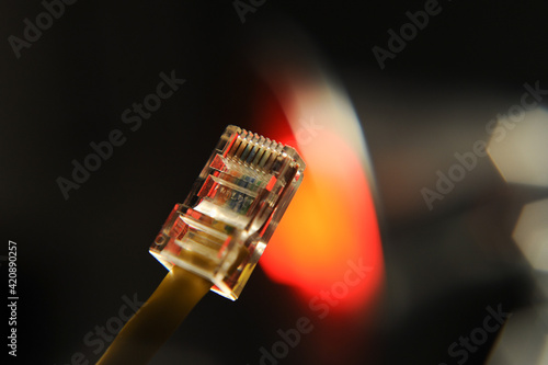 Close-up of an Ethernet cable connector with blurred background lighting, illustrating data transmission hardware used in networking and telecommunications infrastructure