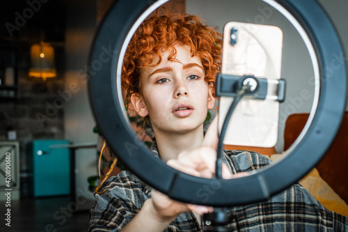 Female blogger with ring light and smartphone records video for social media. Blogger life.