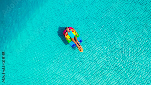 Aerial view. Beautiful woman wearing blue bikini relaxing on an air mattress . A sexy young girl. Holiday person. Amazing sea nature background.