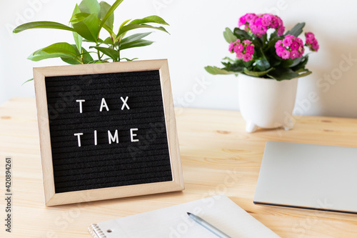 Tax time board, laptop and potted plants on the table.