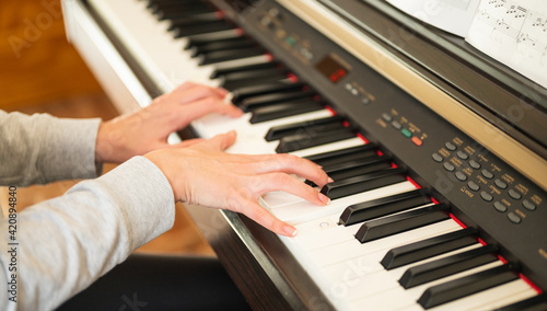close-up of woman's hands learning to play the electronic piano