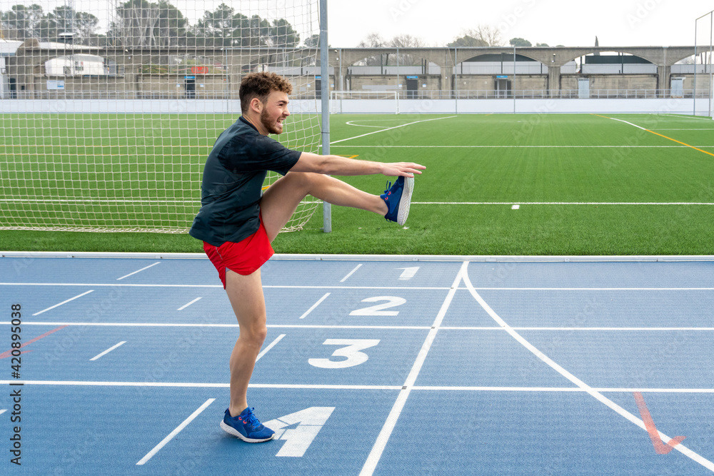 Happy boy wearing sports clothes doing warm-up before workout in the stadium.