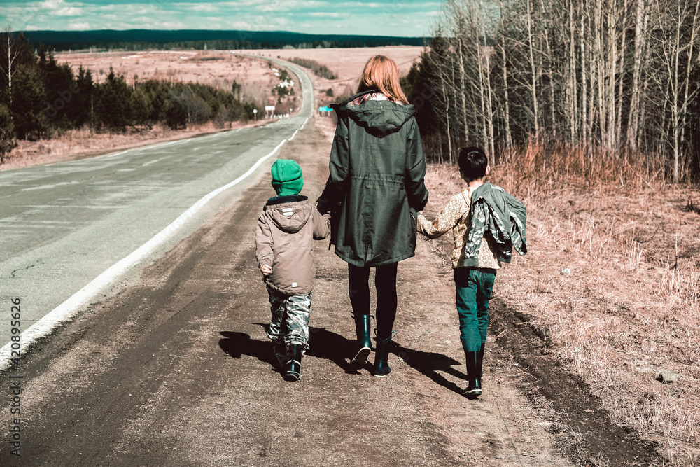 Mother and sons walking along stretch of remote road, Ural, Sverdlovsk, Russia Mother and sons walking along stretch of remote road, Ural, Sverdlovsk, Russia