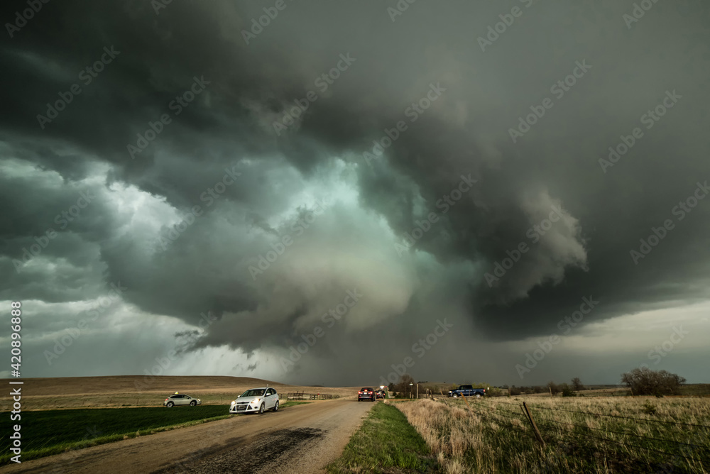 Monster supercell with developing wall cloud moves across central Kansas and later forms a destructive, EF-3 rated tornado destroyed property. Storm chasers observing storm on dirt road, USA Monster supercell with developing wall cloud moves across central Kansas and later forms a destructive, EF-3 rated tornado destroyed property. Storm chasers observing storm on dirt road, USA