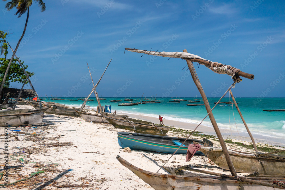 Traditional wooden dhow boats on the White Sand Beach with amazing turquoise water in the Indian ocean at Nungwi village, Zanzibar, Tanzania