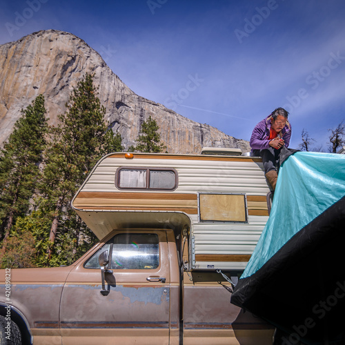 Climber on top of campervan setting up tent, Yosemite National Park, California, USA photo