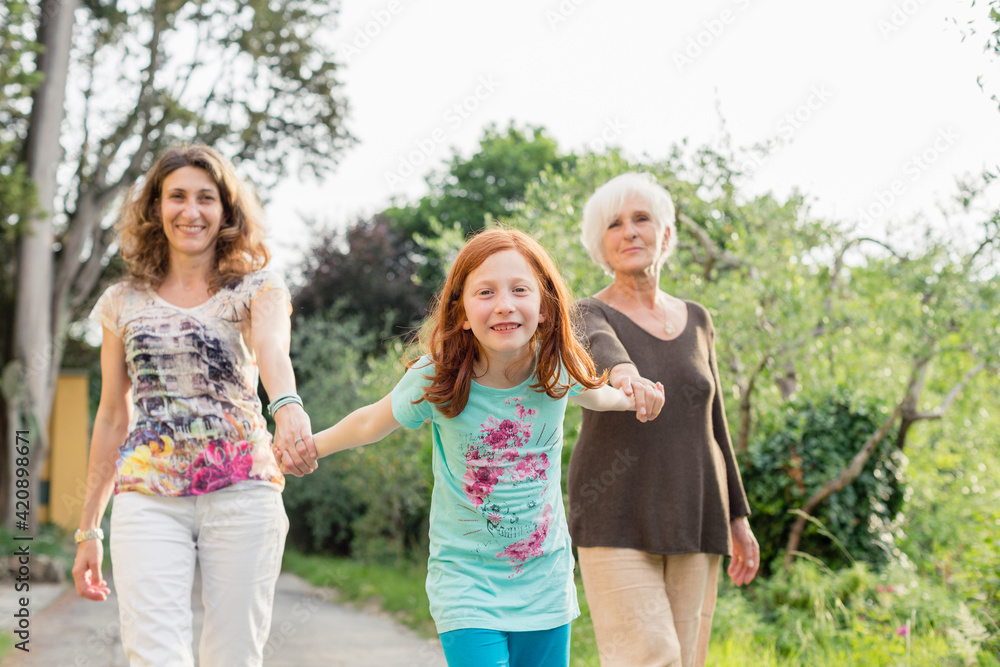Girl on rural road holding hands with mother and grandmother, portrait Girl on rural road holding hands with mother and grandmother, portrait