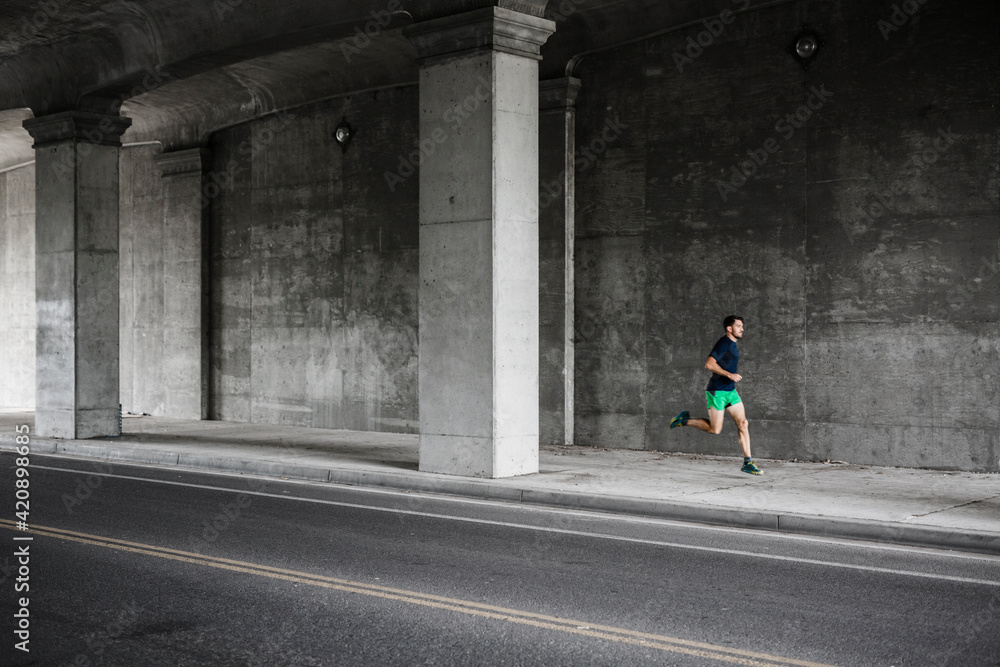 Young male runner running through underpass Young male runner running through underpass