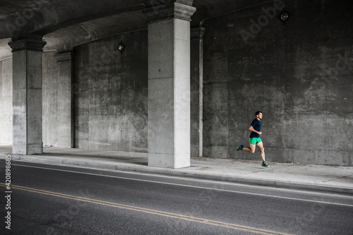 Young male runner running through underpass
