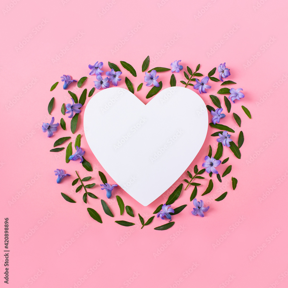 Hyacinth flowers and green leaves on a pink background. Heart empty frame for text