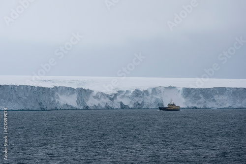 Ship passing ice cliffs of  polar ice cap, Austfonna Nordaustlandet, Svalbard, Norway photo