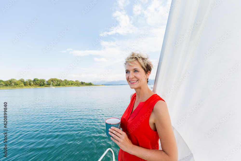 Mature woman having coffee while sailing on Chiemsee lake, Bavaria, Germany Mature woman having coffee while sailing on Chiemsee lake, Bavaria, Germany
