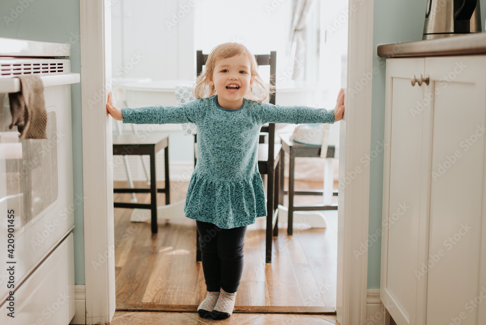 Female toddler standing in kitchen doorway, portrait Female toddler standing in kitchen doorway, portrait