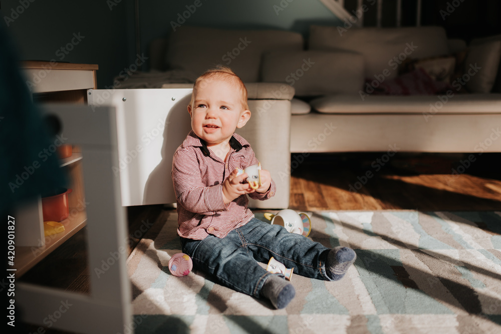 Baby boy sitting playing on living room rug Baby boy sitting playing on living room rug