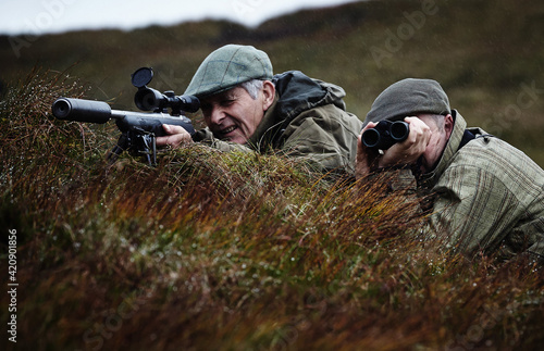 Man and gamekeeper deer stalking on moorland, Scottish Highlands photo