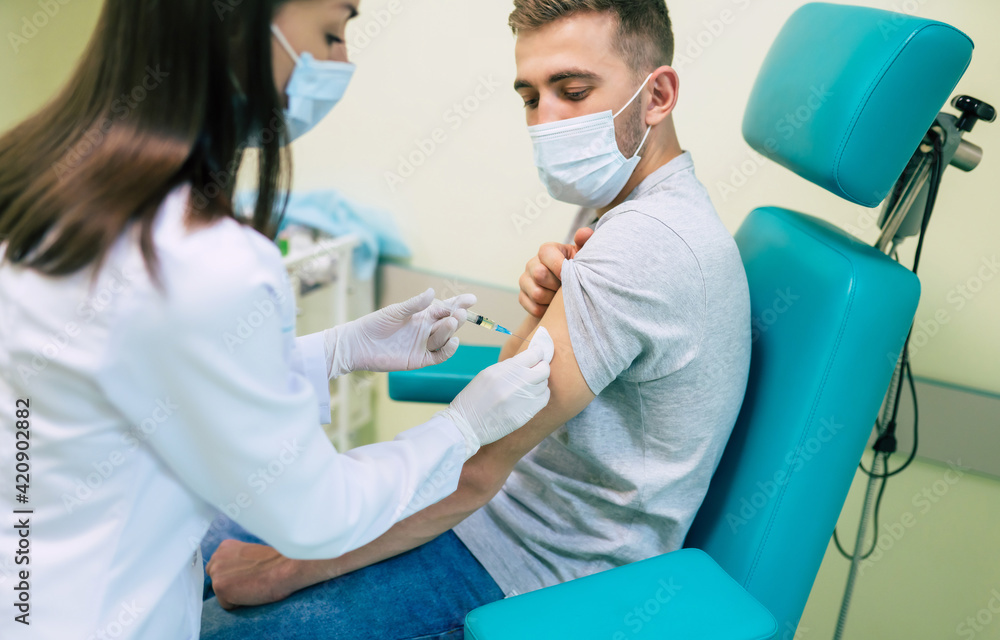 Covid-19 or coronavirus vaccine doctor holding syringe and using cotton before making injection to the patient in the medical mask. Covid-19 or coronavirus vaccine doctor holding syringe and using cotton before making injection to the patient in the medical mask.