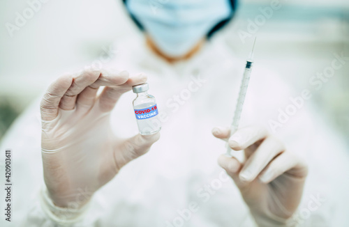 Doctor  nurse  or a scientist in blue gloves holding covid-19 vaccine disease preparing for human clinical trials vaccination shot  medicine  and drug concept.