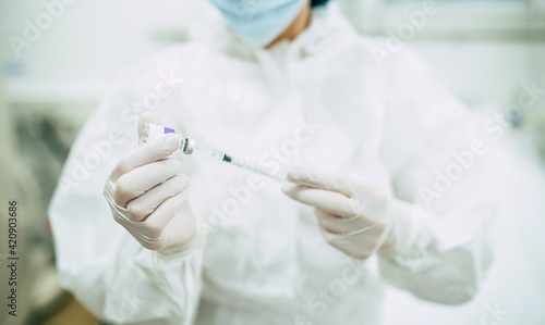 Doctor, nurse, or a scientist in blue gloves holding covid-19 vaccine disease preparing for human clinical trials vaccination shot, medicine, and drug concept.