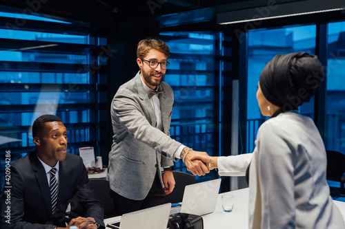 Businessman and female client shaking hands over conference table meeting