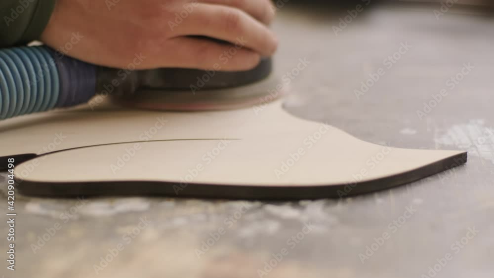 A carpenter grinds a piece of wood, plywood product made on a cnc laser machine with a grinder A carpenter grinds a piece of wood, plywood product made on a cnc laser machine with a grinder