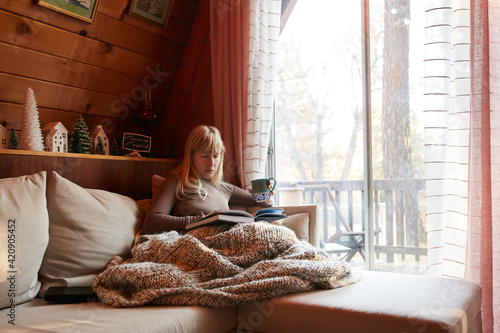 Woman reading book on sofa at home