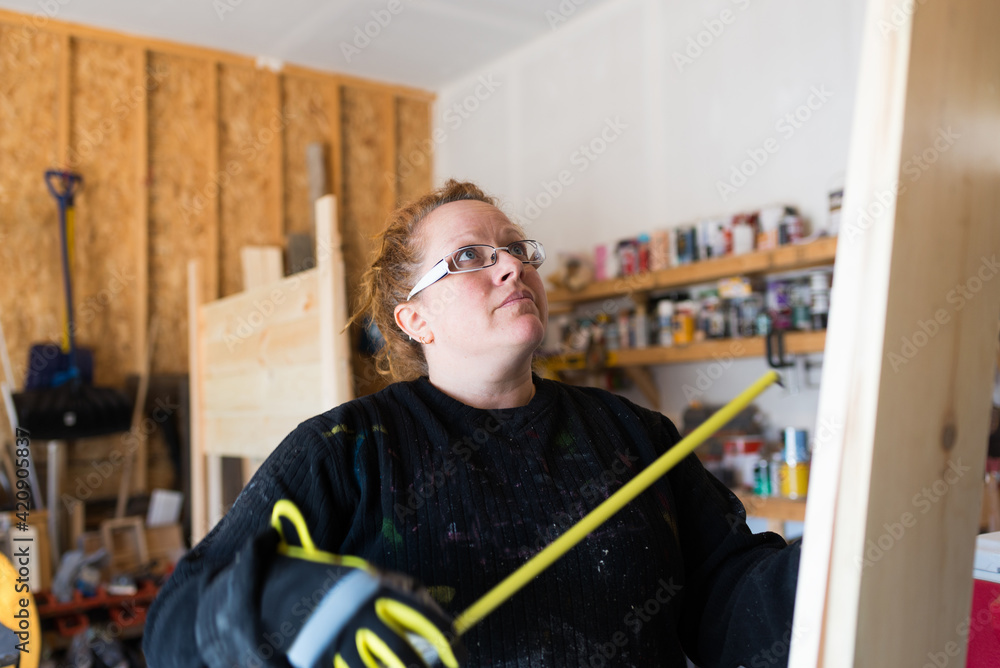 Mature female carpenter looking up at wood planks in workshop Mature female carpenter looking up at wood planks in workshop