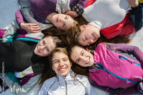Five teenage girl skiers lying in a circle in snow, overhead portrait, Tyrol, Styria, Austria