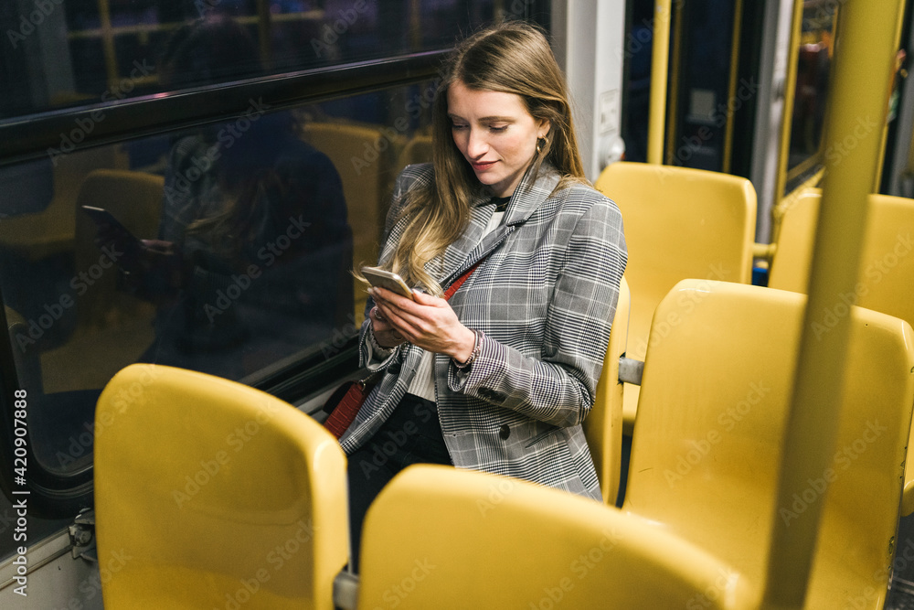 Young woman with long blond hair on carriage looking at smartphone at night Young woman with long blond hair on carriage looking at smartphone at night