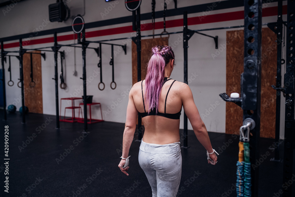 Young woman with purple ponytail training in gym, rear view Young woman with purple ponytail training in gym, rear view