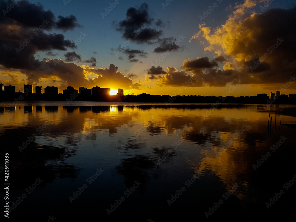 Obraz premium Por do sol em uma lagoa com reflexos de nuvens e prédios na água
