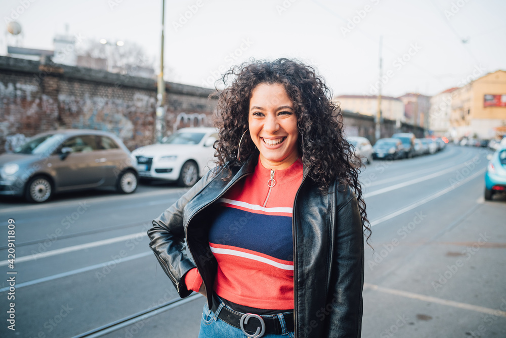 Mid adult woman with long curly hair on city sidewalk Mid adult woman with long curly hair on city sidewalk