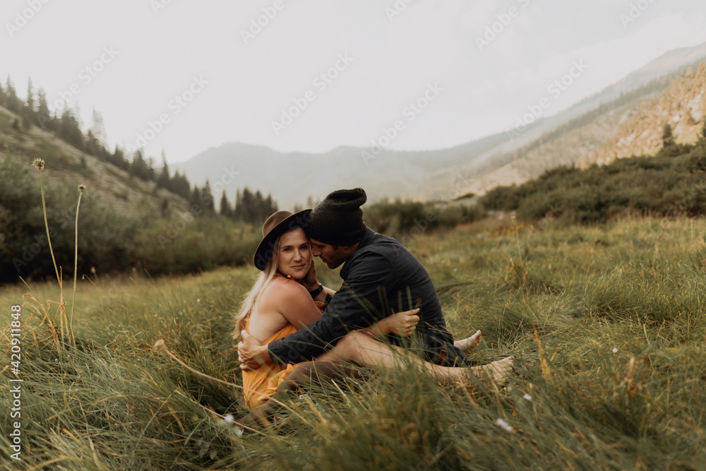 Mid adult couple sitting down hugging in rural valley, portrait, Mineral King, California, USA Mid adult couple sitting down hugging in rural valley, portrait, Mineral King, California, USA