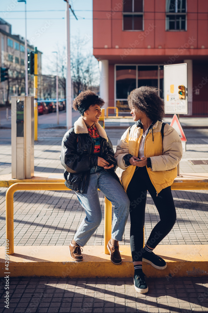 Two cool young women chatting at city tram station Two cool young women chatting at city tram station