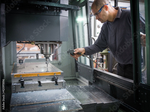 Knife factory worker operating cutting machinery